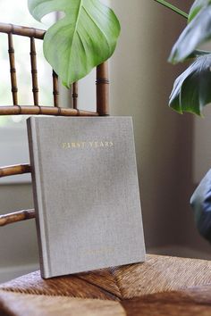 a white book sitting on top of a wooden table next to a green leafy plant