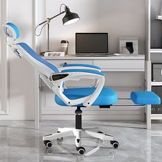 a blue office chair sitting in front of a computer desk