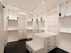 an empty walk - in closet with white shelves and drawers