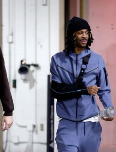 a man with a cast on his arm walking down the street while holding a water bottle