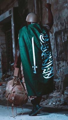 a man walking down the street with a bag on his back and an army green cover over his shoulder