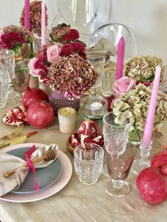 the table is set with pink flowers, apples and other items for an elegant dinner