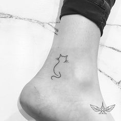 a black and white photo of a small cat tattoo on the left side of the foot