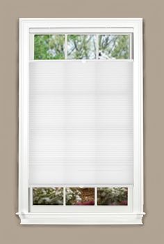 an open window with white blinds in front of the window and green trees behind it