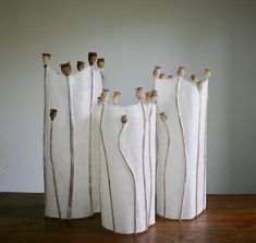 four white vases sitting on top of a wooden table