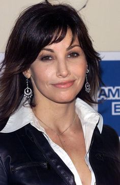 a close up of a person wearing earrings and a leather jacket with a white shirt