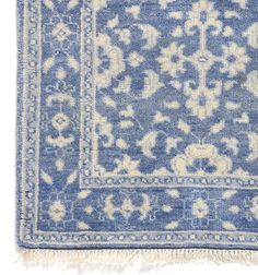 a blue and white rug with an intricate design on the middle, fringed edges