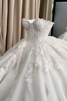 a white wedding dress on display in front of curtains