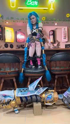 a woman with blue hair sitting on top of a chair next to a table and chairs