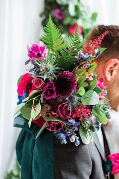 a man wearing a suit and tie holding a bouquet of flowers in his back pocket