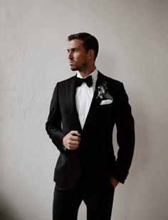 a man in a tuxedo is posing for a photo with his hands in his pockets