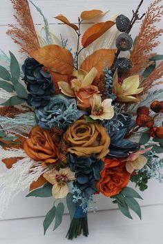 an arrangement of flowers and foliage on a white background with wood planks in the background