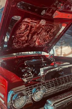 an old red car with its hood open