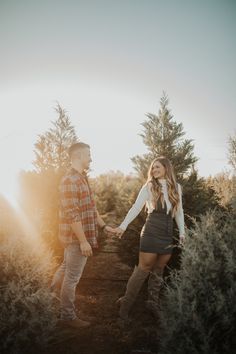 an engaged couple holding hands and walking through the woods