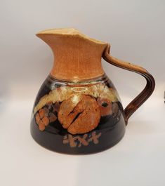 a brown and black ceramic pitcher sitting on top of a table