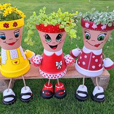 three garden planters sitting on top of a wooden bench with flowers in their heads