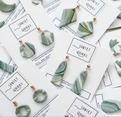 some green and white earrings sitting on top of each other next to cards with the words sweet quiks written in them