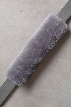 a gray belt with fur on it sitting on top of a floor next to a wall