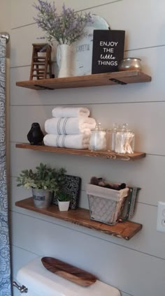 bathroom shelves with towels, plants and other items on them in the corner of a room