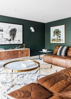 a living room with leather couches and a coffee table in front of a painting on the wall