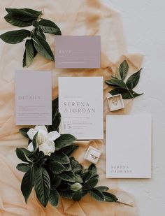 the wedding stationery is laid out with flowers and greenery