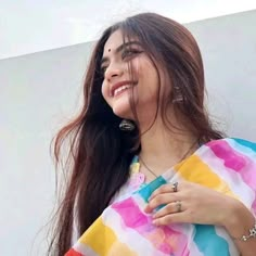 a woman with long hair wearing a multicolored sari and smiling at the camera