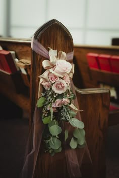 flowers are tied to the back of a church pew