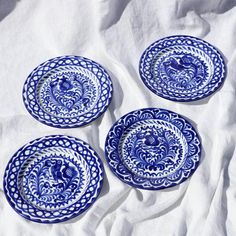 four blue and white plates sitting on top of a bed