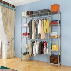 a closet with clothes and bags hanging on the rack in front of a blue wall