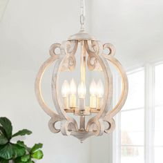 a white chandelier hanging from the ceiling in a room with potted plant