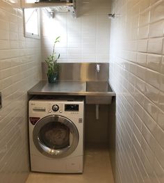 a washer and dryer in a small room with white tiles on the walls