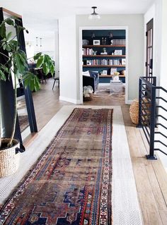 a large rug is on the floor in front of a bookshelf and stairs