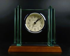 a clock sitting on top of a wooden table next to a black wall and floor