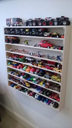 a white shelf filled with lots of toy cars on top of it's sides