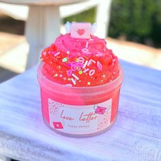 a cup filled with pink frosting and sprinkles on top of a table