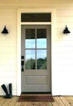 the front door to a house with two black boots on the porch and one gray boot sitting next to it