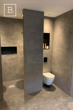 a modern bathroom with concrete walls and flooring, toilet in the corner between two tall columns