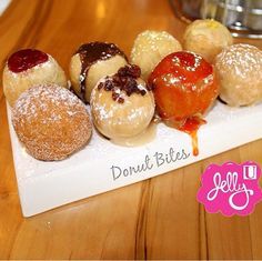 a white plate topped with donuts covered in icing and toppings on top of a wooden table