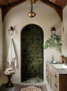 a bathroom with a green tile wall and wooden ceiling, along with a rug on the floor