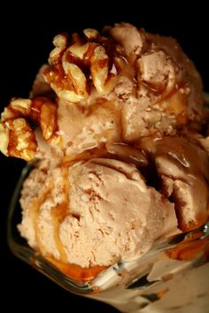 two scoops of ice cream with walnuts and caramel sauce in a glass dish