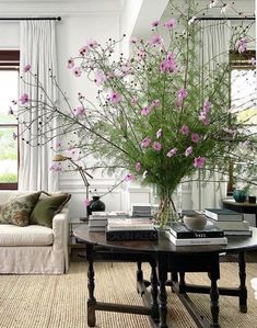 a living room filled with lots of furniture and flowers in a vase on top of a table