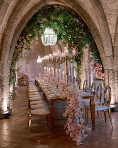 a long table with flowers and candles is set up in an archway for a formal function