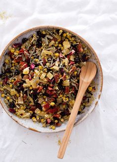 a bowl filled with food next to a wooden spoon on top of a white table