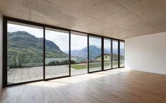 an empty room with wooden floors and large windows overlooking the mountain range in the distance