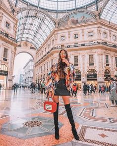 a woman is standing in the middle of a shopping mall with her hand on her hip