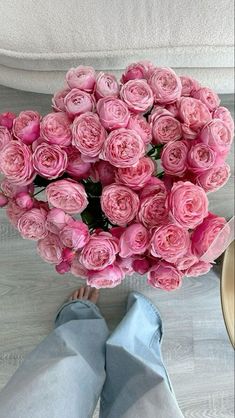 a bouquet of pink roses sitting on the floor next to someone's feet