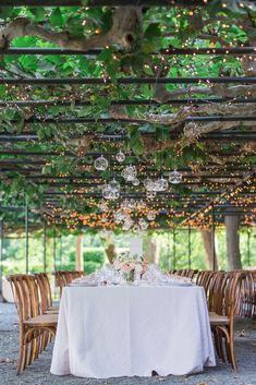 an outdoor dining area with tables, chairs and chandeliers hanging from the ceiling