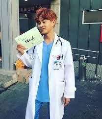 a man in a white lab coat is holding up a sign that says kim min suk doctor crush