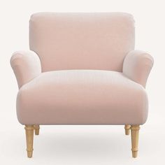 a pink chair sitting on top of a white floor next to a wooden legrest