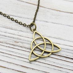 a gold necklace with an intricate design on it's link and is sitting on a wooden surface